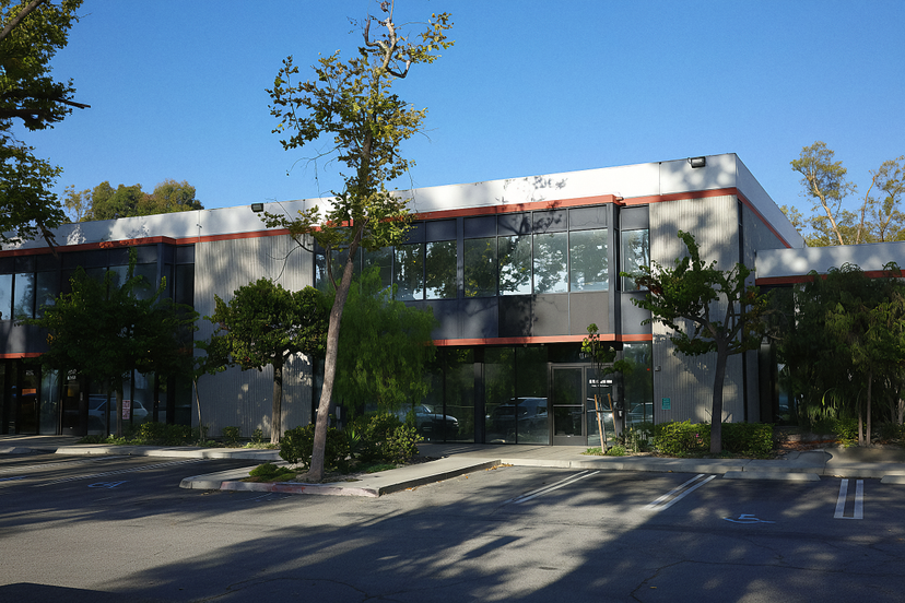 Exterior shot of a modern two-story office building with large windows and parking lot
